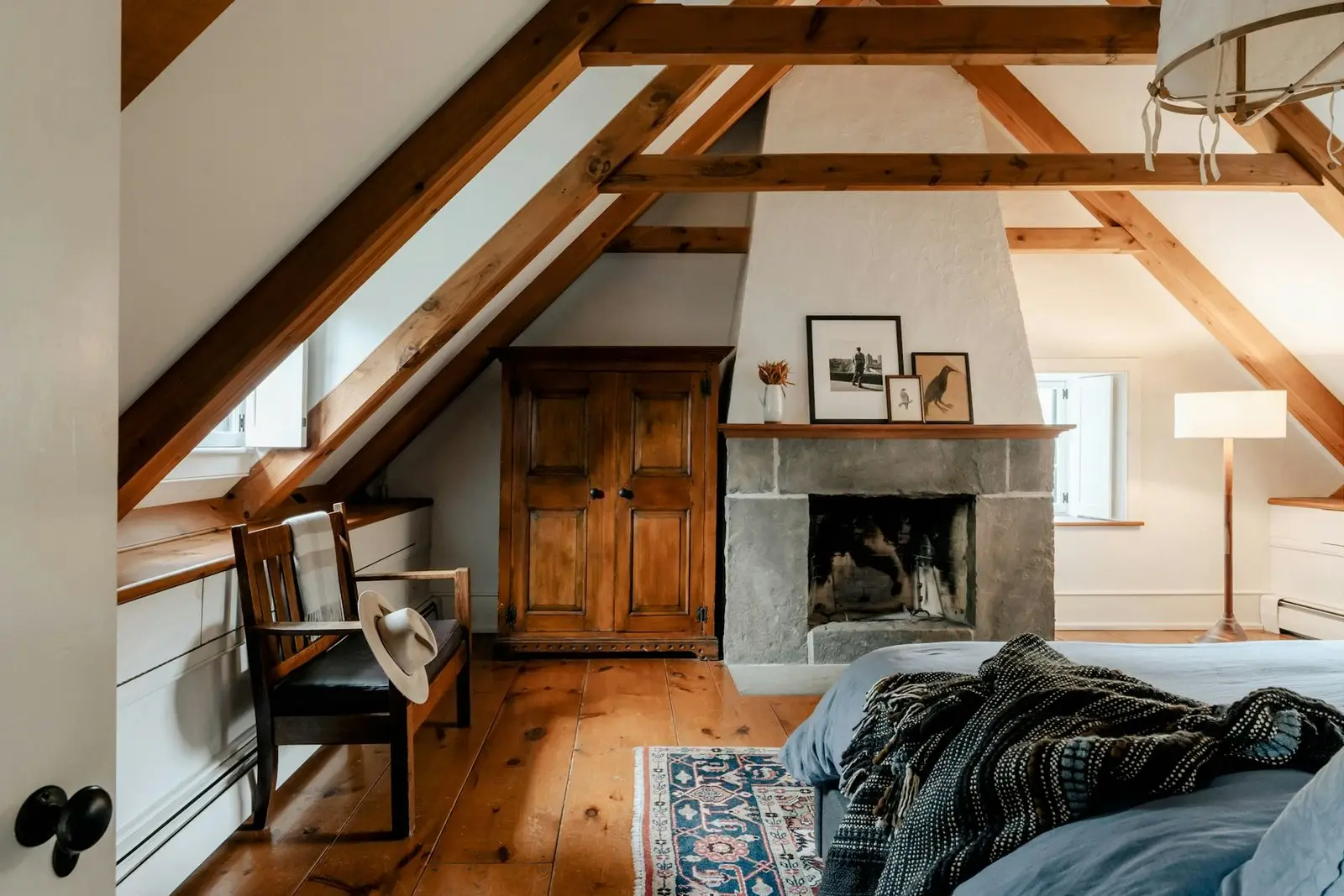 Main bedroom under exposed beams, with an open fireplace